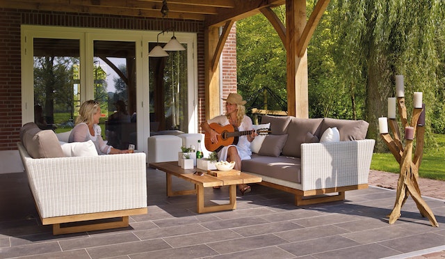 Two tenants relax on outdoor couches on a patio one tenant plays guitar as the other listens